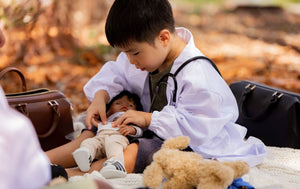 Boy puts bandage on miniland doll with his doctor set