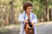 Load image into Gallery viewer, A little girl holds open her doctor bag while wearing a lab coat and stethoscope
